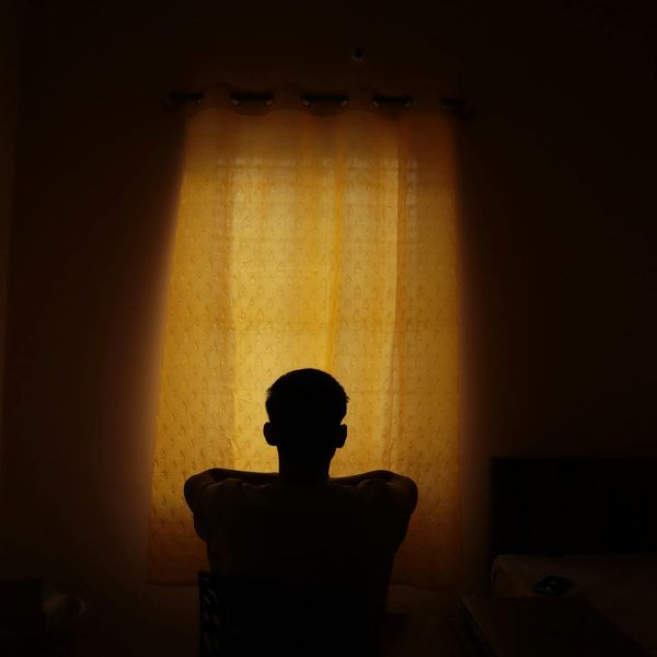 Person meditating peacefully in a room with soft, warm light.